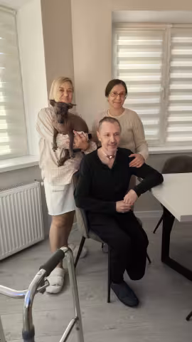 man sitting with two women standing behind him