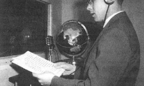 young man in a sound studio wearing headphones and reading into a microphone