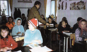 a man hands out literature in a classroom of students