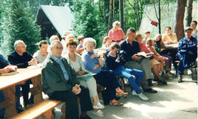 a group of people sitting outdoors in a camp setting