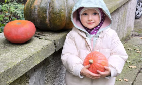 a small girl holding a pumpkin