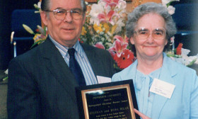 a man and woman stand holding a plaque