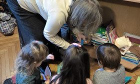 a woman bends over to speak with a group of children