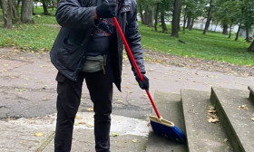 man sweeps leaves off church porch steps