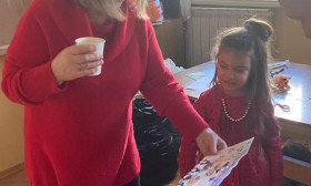 woman examining a young girl's artwork