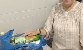 woman smiling as she stands next to a bag of products