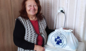 woman smiling as she stands next to a bag of products