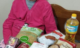 an elderly woman sitting at a table full of products