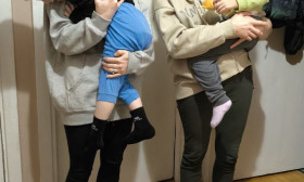 two women standing and holding children