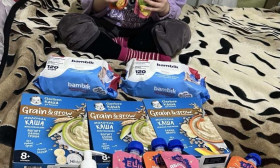 Happy young child with baby food, diapers, and toiletries, showcasing essential baby care products and infant nutrition.